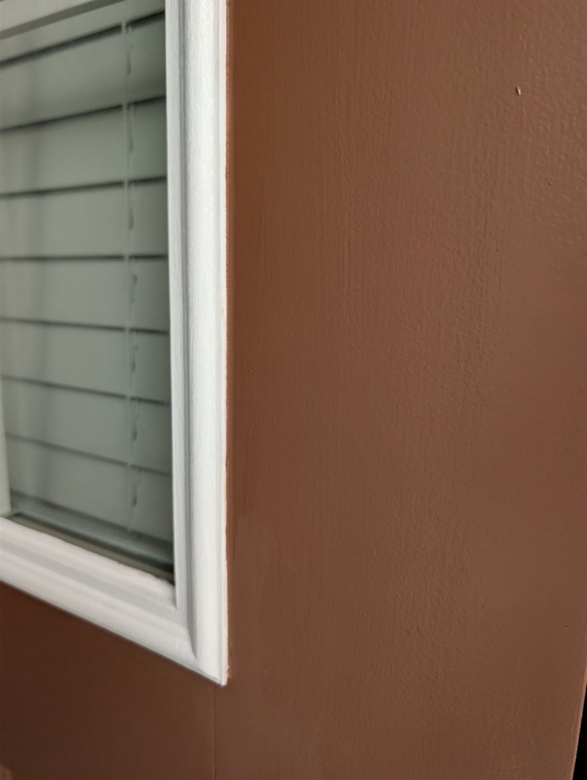 Close-up of the finished corner where brown exterior door enamel meets white detailed trim